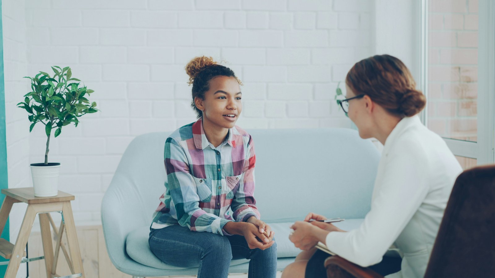 A client speaking openly with a counselor in a bright, calm therapy room